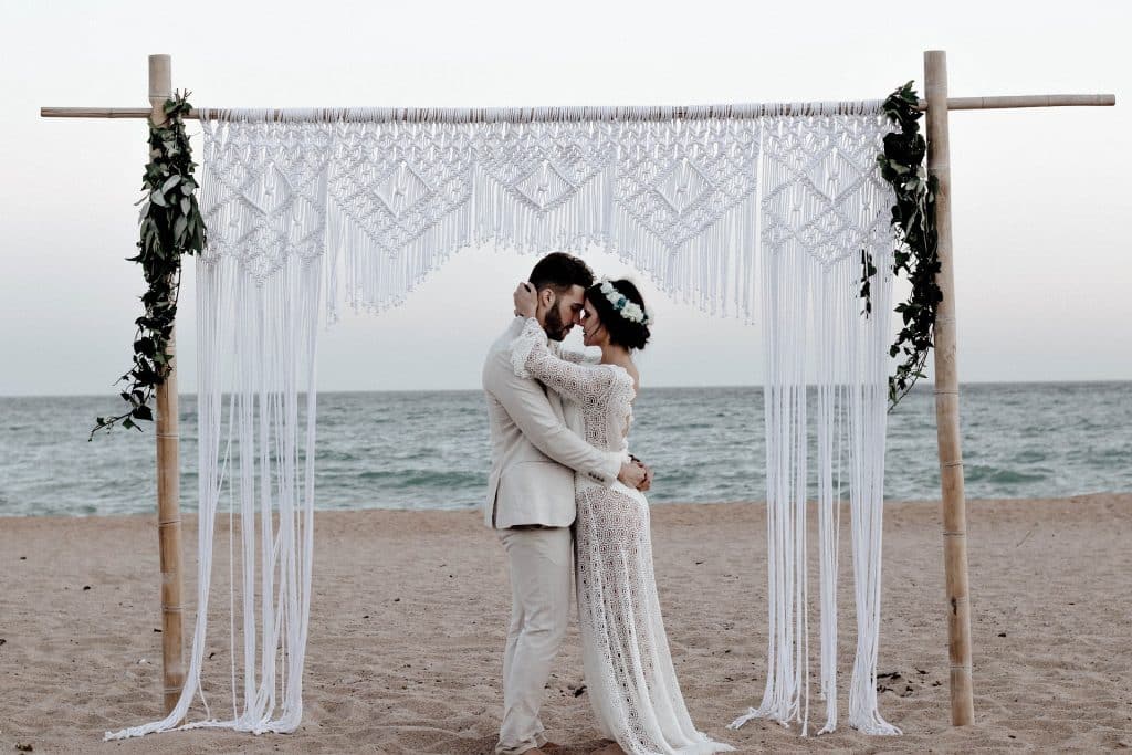 Innig umarmendes Brautpaar am Strand mit Blick auf das Meer